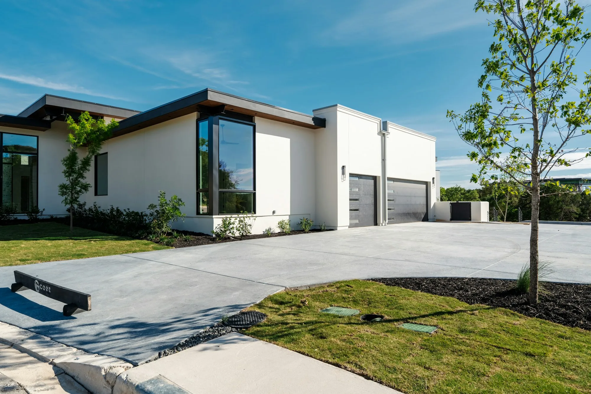 Modern home with a concrete driveway and steps beside a green lawn